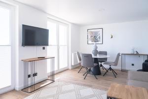 a living room with a tv and a table and chairs at JOHOUSE Apartment 12 in Warnemünde