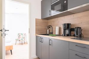a kitchen with white cabinets and a counter top at JOHOUSE Apartment 12 in Warnemünde +8 photos