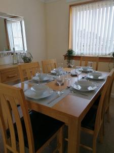 einen Holztisch mit Tellern und Weingläsern darauf in der Unterkunft Beautiful three bedroom seaside retreat in Prestonpans