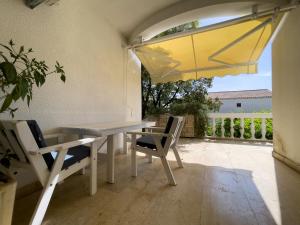 a table and chairs on a patio with a yellow umbrella at Apartments Ante in Mandre