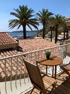 d'un balcon avec une table, des chaises et des palmiers. dans l'établissement Hostellerie Provencale, à Port-Cros