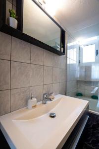 a bathroom with a white sink and a mirror at Eden’s garden in Chania Town +10 photos
