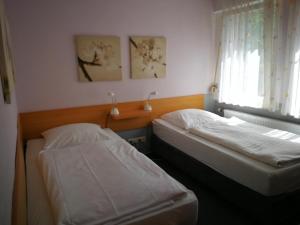 2 Betten in einem Zimmer mit Fenster in der Unterkunft Pension Zum Angestellten in Porta Westfalica