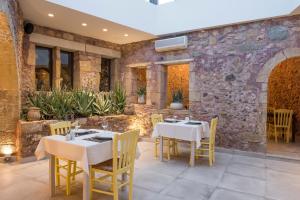 a dining room with tables and chairs and a stone wall at Spilia Village Hotel & Villas in Spiliá