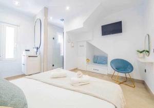 a white bedroom with a large bed and a blue chair at Casa Moises By Solymar Holiday in Torre del Mar