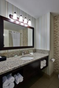 bagno con lavandino, specchio e asciugamani di Country Inn & Suites by Radisson, Williamsburg Historic Area, VA a Williamsburg