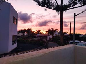una puesta de sol sobre una casa con una palmera en Casa las Águilas, Lajares, en Lajares