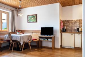 a kitchen and dining room with a table and a television at Haus Thurn Apartment A in Castelrotto
