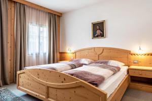 a large wooden bed in a room with a window at Haus Thurn Apartment A in Castelrotto