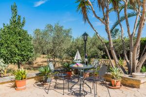 a patio with a table and chairs and palm trees at Villa Moreno in Pollença
