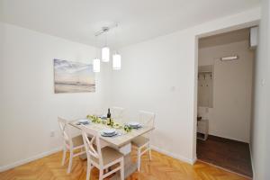 Un comedor blanco con una mesa y sillas. en Unico apartman, en Kotor