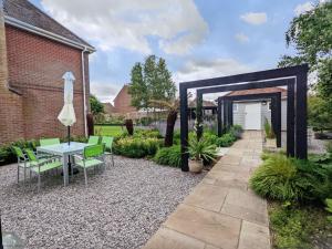 a patio with a table and chairs in a garden at Little Maplewood, Tangmere in Tangmere