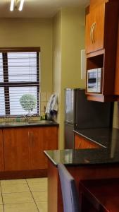 Homely Apartment, Hatfield, Unit-9 في بريتوريا: مطبخ مع مغسلة وثلاجة