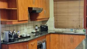 Homely Apartment, Hatfield, Unit-9 في بريتوريا: مطبخ بدولاب خشبي ومغسلة