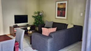 a living room with a blue couch and a tv at Homely Apartment, Hatfield, Unit-9 in Pretoria