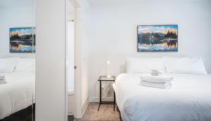 a white bedroom with a bed and a mirror at RendezView by Revelstoke Vacations in Revelstoke