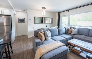RendezView by Revelstoke Vacations في ريفيلستوك: غرفة معيشة مع أريكة زرقاء وطاولة