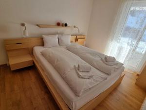 Elle comprend un grand lit avec des draps blancs et des serviettes. dans l'établissement Modern and bright apartment opposite ski-lift, à Münster