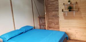a bedroom with a blue bed and a wooden wall at Cabaña los Naranjos con parqueo in Calarcá