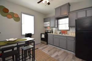 cocina con armarios grises y nevera negra en SuperValue Suite #9 @ East End Revitalized, en Houston