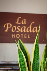 a sign that says la pociada hotel with a plant at La Posada Copan in Copan Ruinas