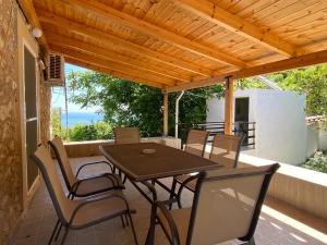 einen Tisch und Stühle auf einer Terrasse mit einem Holzdach in der Unterkunft Barbajonn's Stone House in Monemvasia