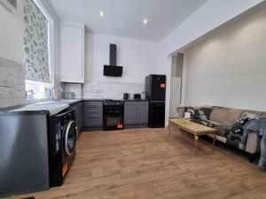 a kitchen with a stove and a couch in a room at Cheerful 4 bedroom close to Uclan, Preston City Center in Preston