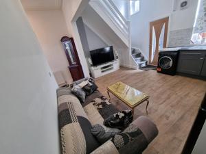 a living room with a couch and a tv at Cheerful 4 bedroom close to Uclan, Preston City Center in Preston