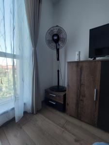 a room with a fan sitting on a stand next to a window at Dabe Hd in Hunedoara