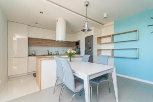 cocina con mesa blanca y sillas azules en Apartamenty Cztery Kąty w Kątach Rybackich en Kąty Rybackie