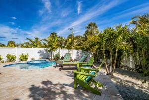 a patio with two green chairs and a pool at Royal Palm: Pool, 2 Blocks to Beach, Close to Dining & Shopping by Anna Maria Life Vacation Rentals in Holmes Beach