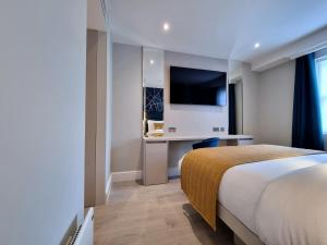 um quarto de hotel com uma cama, uma secretária e uma televisão em NOX Edgware Road em Londres