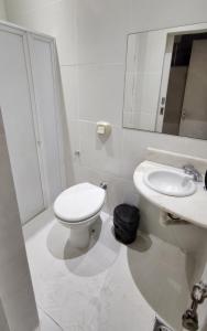a white bathroom with a toilet and a sink at Baixo Copa Guest House in Rio de Janeiro