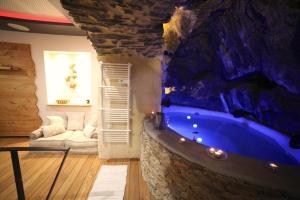 a bathroom with a large blue tub in a stone wall at The Ginkgo Collioure : Amazing Private Jacuzzi built in Rock, 20m from the Beach, A/C, WiFi, Patio... in Collioure
