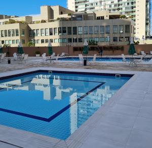 a swimming pool with chairs and umbrellas on a building at Residencial Liberty Barra da Tijuca in Rio de Janeiro