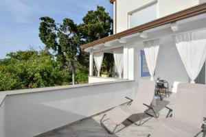 un patio con sillas blancas en una casa blanca en B&B inCentro en Santa Maria di Castellabate