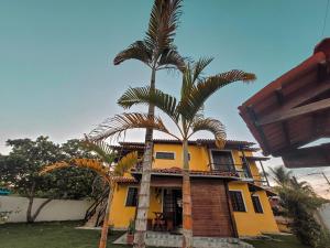 a house with two palm trees in front of it at Pousada Casa da Marina in Ilha de Boipeba