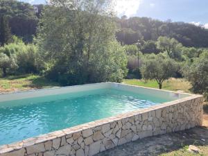 una piscina en un jardín con una pared de piedra en Le Giuncaie - Vigna con alloggio, en Montescudaio