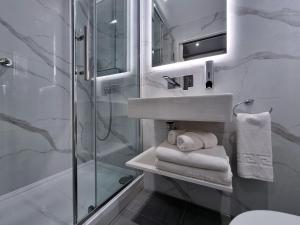 a bathroom with a sink and a shower with towels at NOX Edgware Road in London