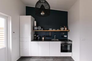 a kitchen with white cabinets and a black wall at Ocean Break Cabins in Sandgerði