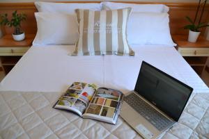 un computer portatile su un letto con una rivista e un libro di Hotel Apogeo a Rimini