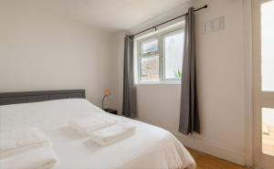 um quarto branco com uma cama com duas toalhas em -NEWLY REFURBISHED- Stylish Apartment 5 minutes from Station w Garden em Brighton & Hove
