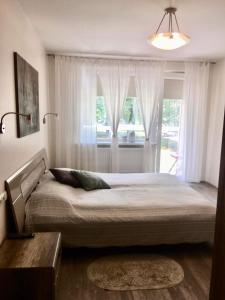 een slaapkamer met een groot bed voor een raam bij Smiltės apartamentai in Birštonas