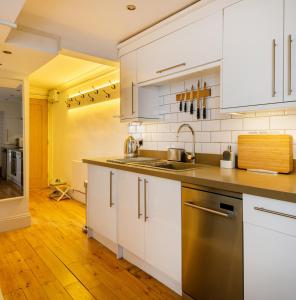 uma cozinha com armários brancos e electrodomésticos de aço inoxidável em -NEWLY REFURBISHED- Stylish Apartment 5 minutes from Station w Garden em Brighton & Hove