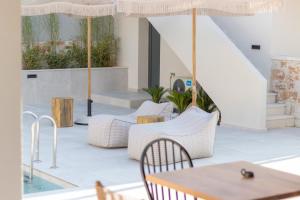 un patio con sillas, mesas y una sombrilla en Rastoni - Relax & Retreat, en Skala Potamias