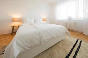 a white bed with white sheets and a rug in a bedroom at apartmán NA NOC V BOHDANČI in Lázně Bohdaneč