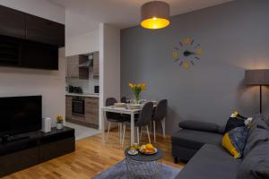 a living room with a couch and a clock on the wall at Kolejowa Apartments Warsaw by Renters in Warsaw
