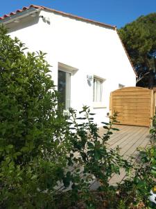 une maison blanche avec une terrasse en bois devant elle dans l'établissement Les Salines Oléron, à Saint-Pierre-dʼOléron