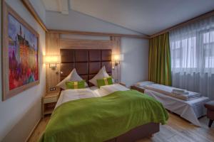 a bedroom with a large bed with a green blanket at Best Western Plus Hotel Füssen in Füssen