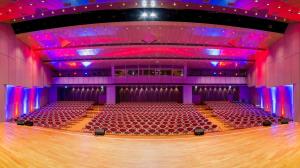 a large auditorium with a wooden floor and purple lights at Best Western Plus Palatin Kongresshotel in Wiesloch